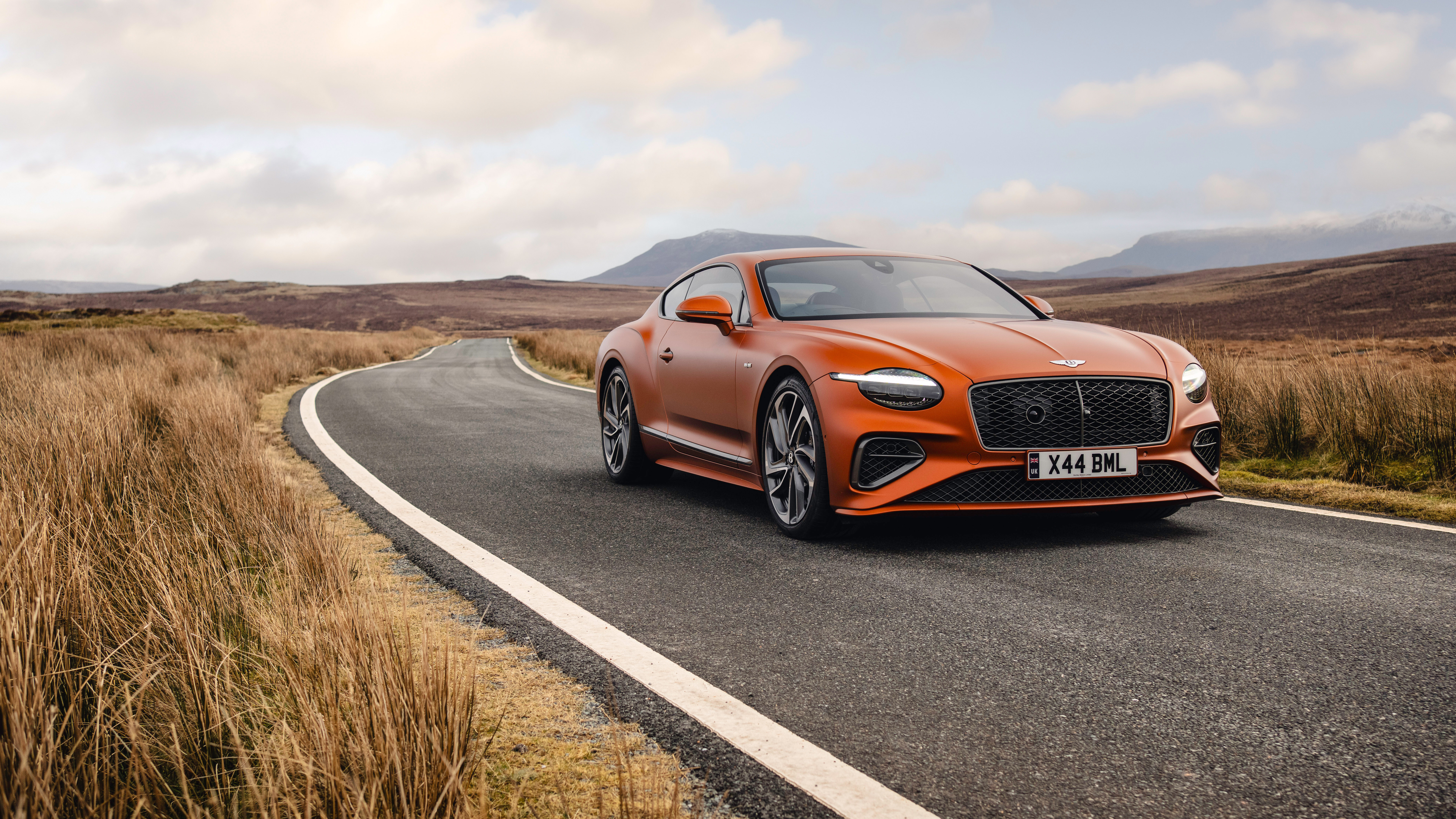 Ein leuchtend orangefarbener Bentley Continental GT Speed, der sein luxuriöses Design und seine beeindruckende Erscheinung zur Schau stellt.