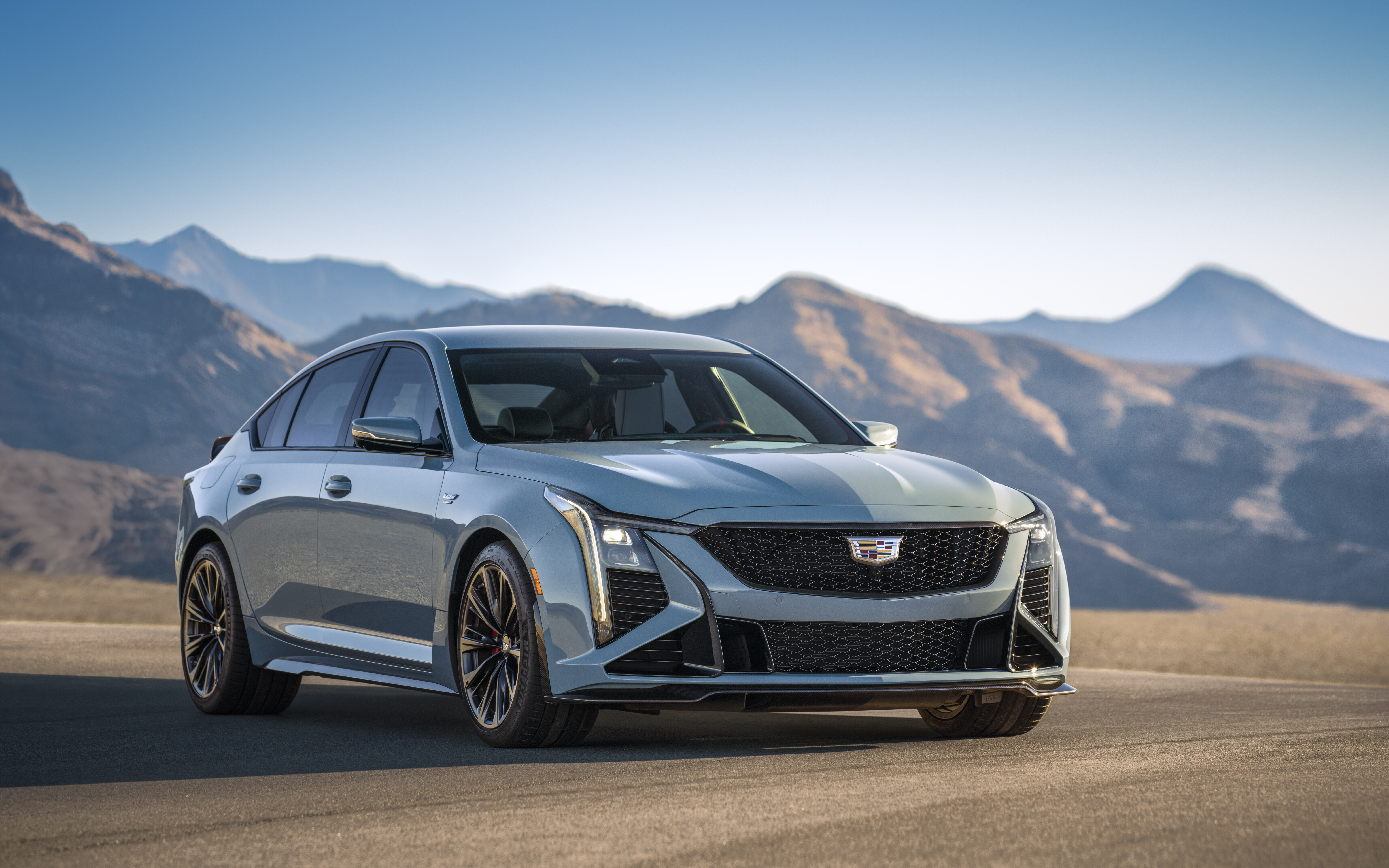 Eine detaillierte Ansicht einer Cadillac CT5-V Blackwing Limousine, wobei der Fokus auf ihrem modernen Kühlergrill, den Scheinwerfern und dem luxuriösen Design des Fahrzeugs liegt.