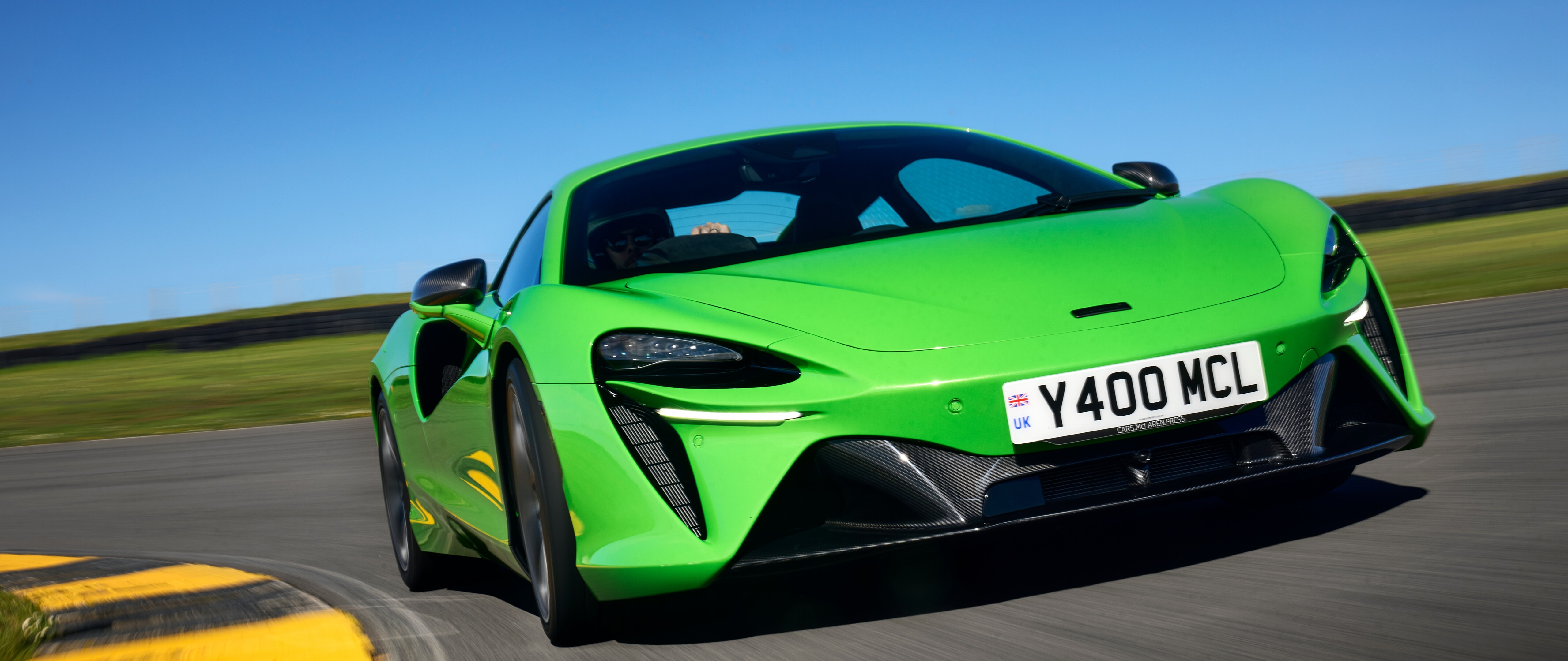 Ein leuchtend grüner McLaren Artura, ein luxuriöser Supersportwagen mit aerodynamischen Linien und einer glänzenden Lackierung.